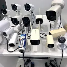 Plusieurs caméras de surveillance extérieures sans fil de différents modèles et couleurs sont exposées sur un présentoir blanc.